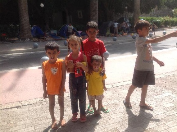 Syrian refugee children smile and pose for a picture after being handed sweets and chocolate